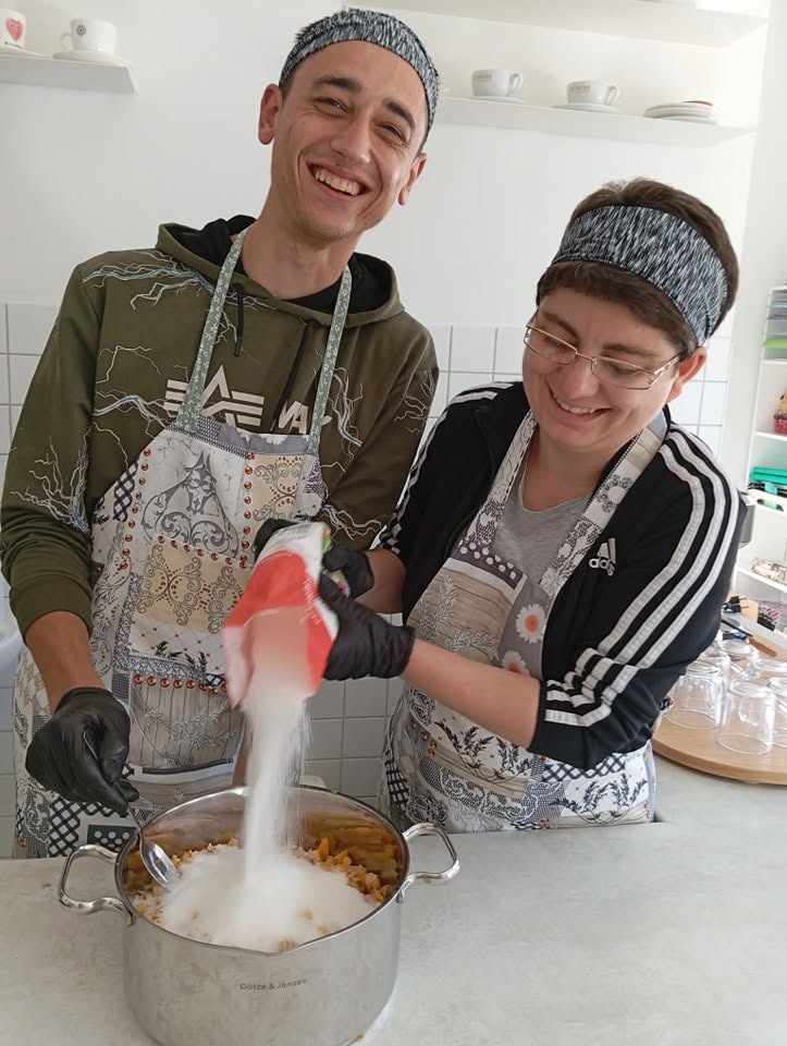 Dwoje uczestników w fartuchach gotuje w pracowni kulinarnej