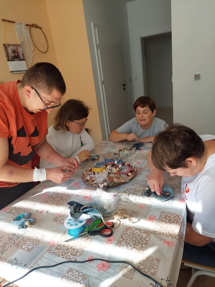 Uczestnicy tworzą ozdoby z koralików przy stole w pracowni rękodzieła