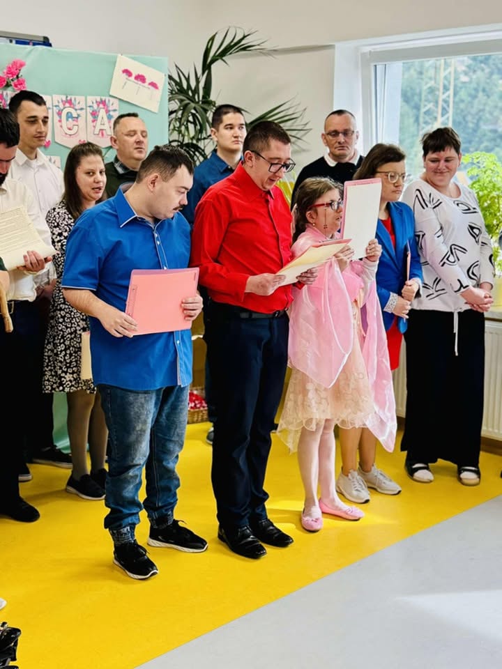 Podopieczni czytają teksty podczas uroczystości w sali ośrodka